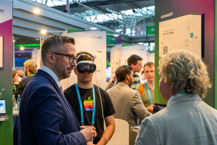 Zu sehen ist Minister Martin Dulig am Messestand. Er bekommt von Prof. Dr. Dirk Winkler das Funktionieren der Softwareplattform erklärt.