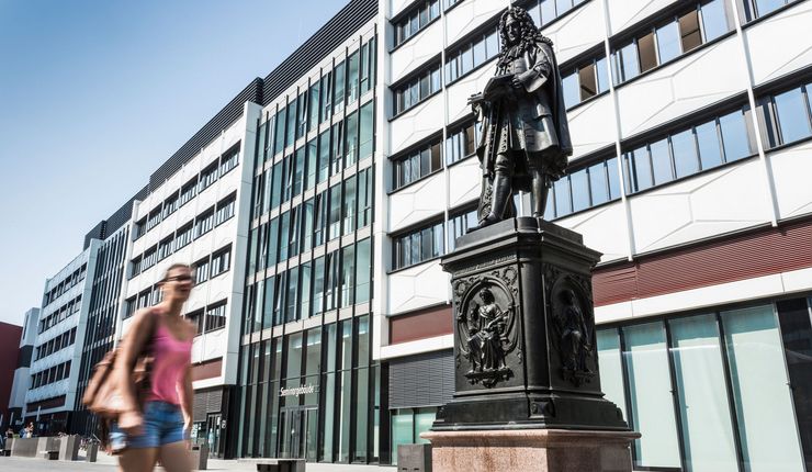 Foto: eine junge Frau läuft auf dem Uniinnenhof am Seminargebäude vorbei