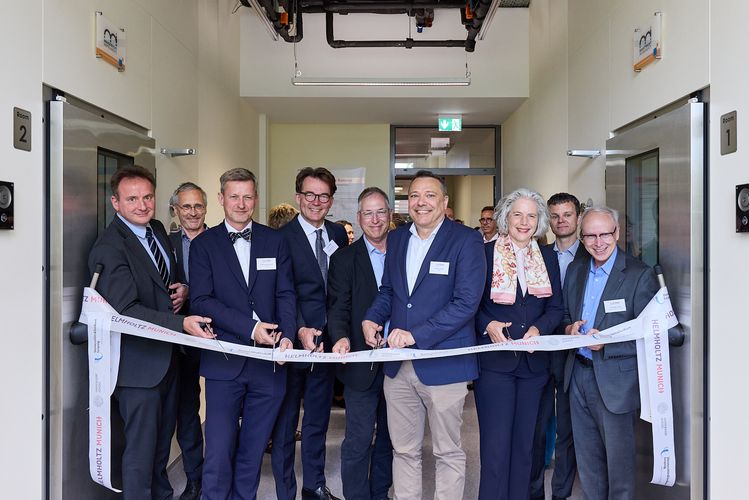Gruppenfoto mit Professoren und Rektorin, die gemeinsam ein Band durchschneiden