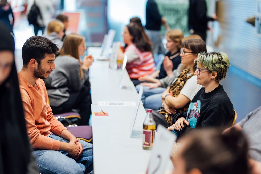 zur Vergrößerungsansicht des Bildes: Foto: Besucher:innen im Gespräch mit Studierenden.