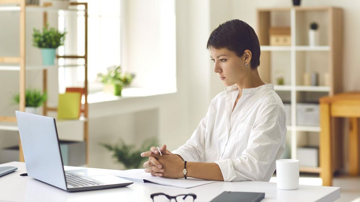 Junge Frau an einem Schreibtisch, auf dem ein Laptop steht