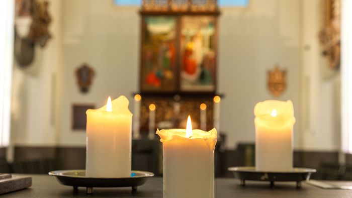 Farbfoto: drei brennende Kerzen auf einem Altar