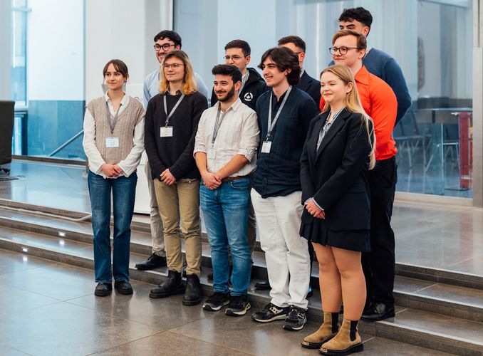 Zu sehen ist eine Gruppe von 10 Personen, die auf einer kleinen Treppe im Paulinum stehen.