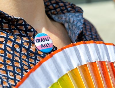 Am Kleidungsstück einer Person ist ein Button befestigt mit der Aufrschrift "trans ally"