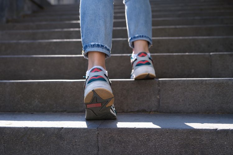 Füße in Sportschuhen steigen eine Treppe hinauf