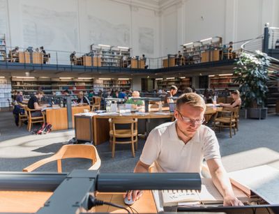 Mann liest in der Bibliothek