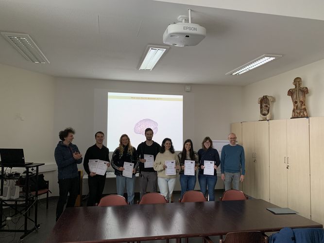 A group of people standing in front of the projection wall with award certificates in their hands