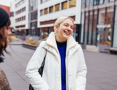 Studienbotschafterin Vivi steht auf dem Campus und lacht mit einer Studentin, Foto: Christian Hüller