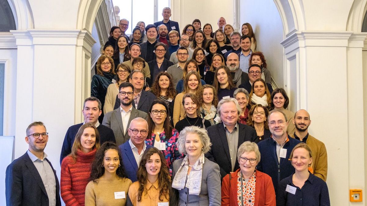 enlarge the image: A group of people stand spread out on a staircase, all facing the camera