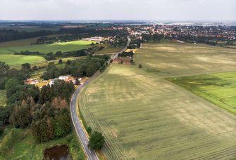 Luftbild von einer Straße, die auf eine kleine Stadt zuführt