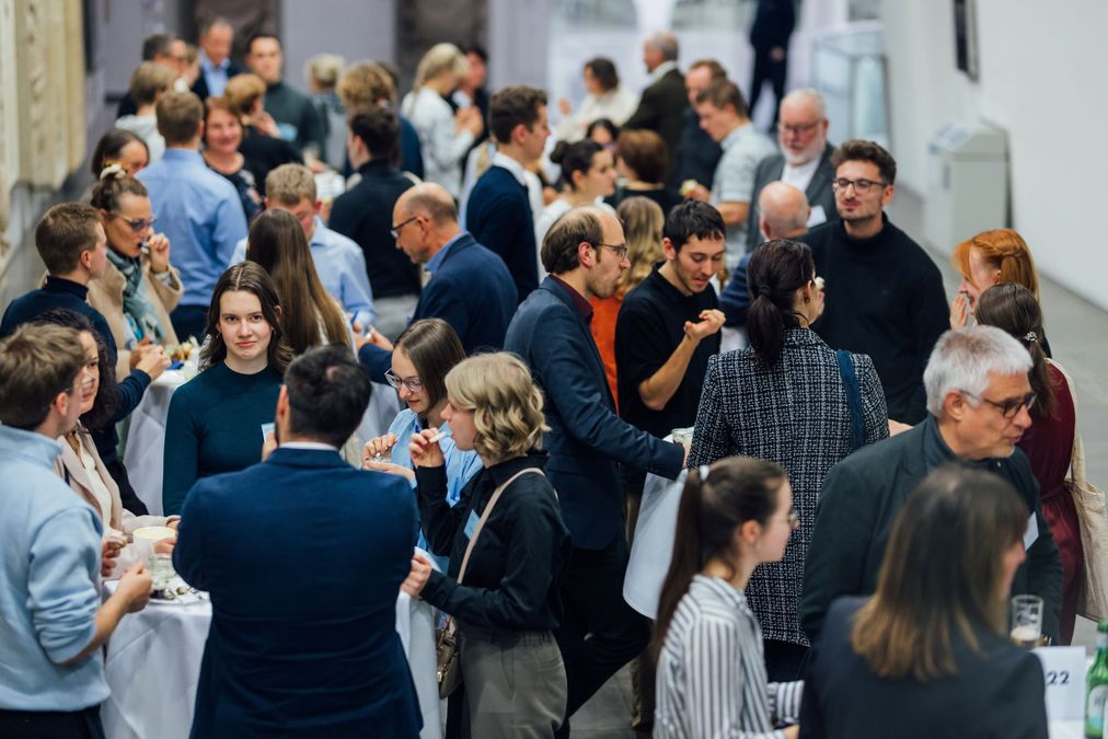 zur Vergrößerungsansicht des Bildes: Fördernde und Stipendiaten stehen an Stehtischen, sie essen, trinken und unterhalten sich