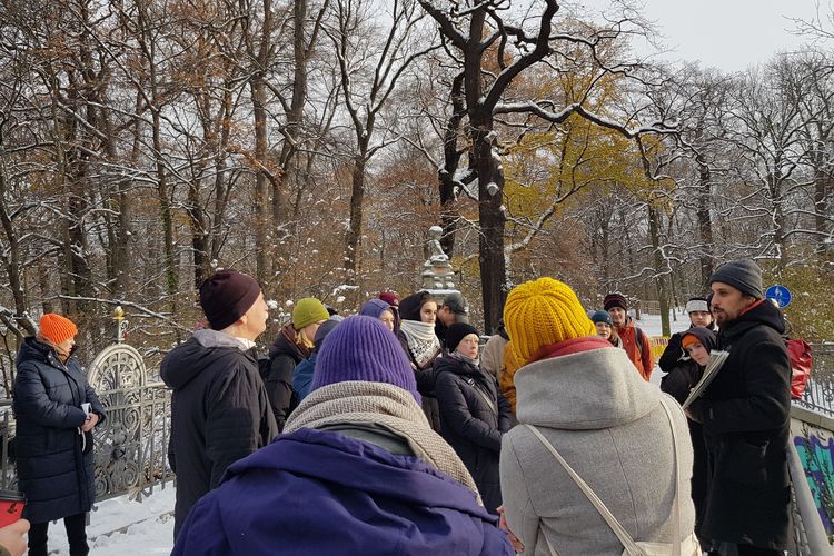 Gruppe von Menschen steht im Schnee bei Sonnenschein um einen Sprecher