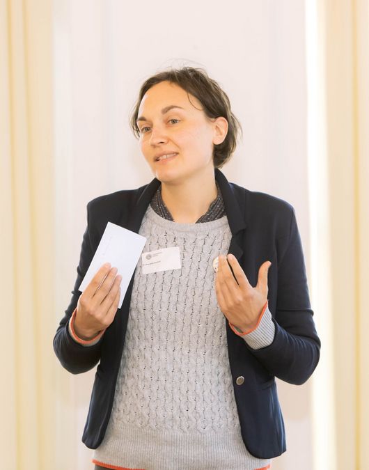 zur Vergrößerungsansicht des Bildes: Dr. Kornelia Ehrlich steht vorm Publikum und stellt die Research Academy Leipzig vor.