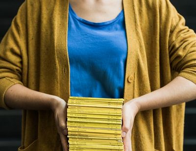Frau hält eine Stapel Bücher in den Händen