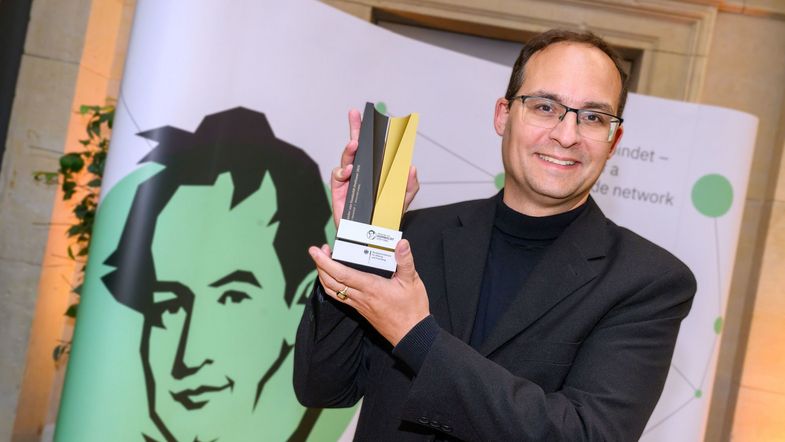 Professor Daniel Kráľ holding a Humboldt Foundation trophy.