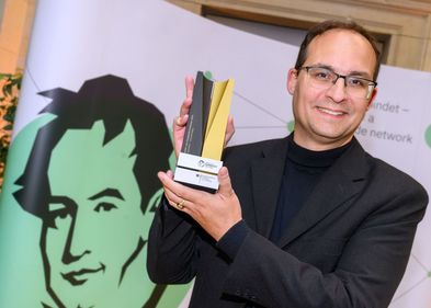 Professor Daniel Kráľ holding a Humboldt Foundation trophy.