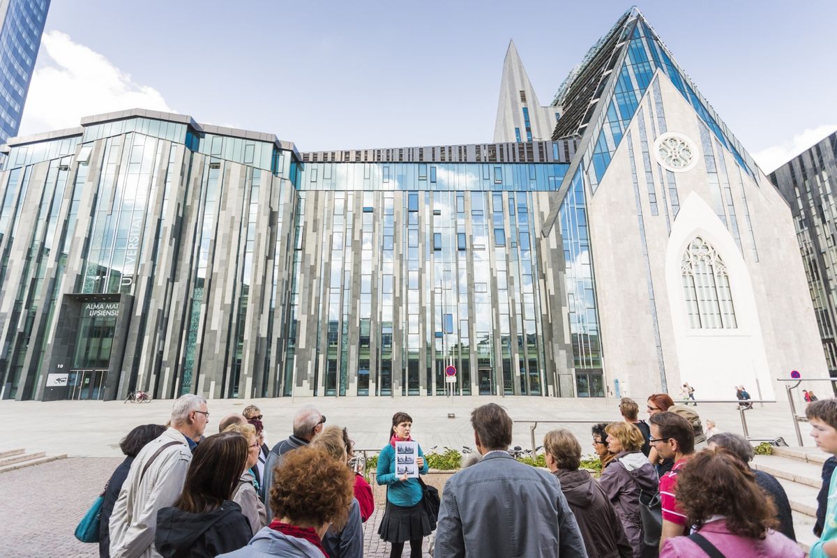 zur Vergrößerungsansicht des Bildes: Foto: eine Gästegruppe mit Führerin steht auf dem Augustusplatz mit Blick auf das Paulinum