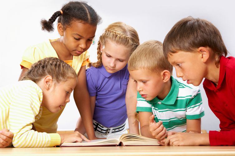 Auf dem Foto sind fünf Kinder zu sehen, die sich gemeinsam ein Buch anschauen, Foto: Colourbox.de