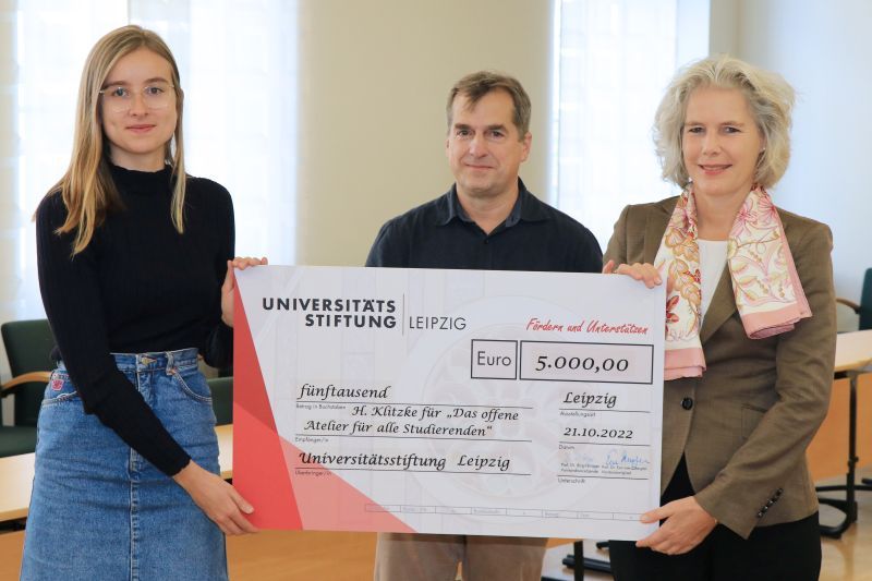 zur Vergrößerungsansicht des Bildes: Farbfoto: Prof. Dr. Eva Inés Obergfell und Prof. Dr. Harald Krautscheid von der Universitätsstiftung überreichen den symbolischen Scheck an die Fördermittelempfängerin Hannah Klitzke