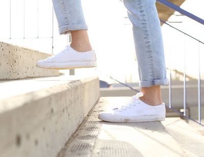 Farbfoto von den Füßen einer Frau in Sneakers, die eine Treppe hochläuft