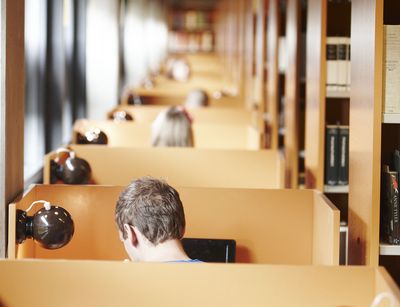 Zu sehen sind Menschen in eine Bibliothek.