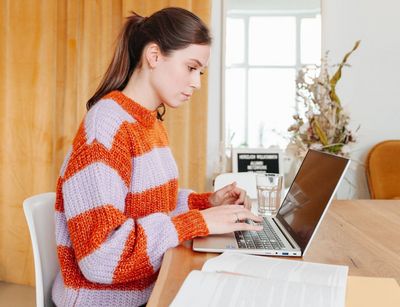 Junge Frau sitzt am Schreibtisch, vor ihr steht ein aufgeklappter Laptop, Foto: Grit Hartung