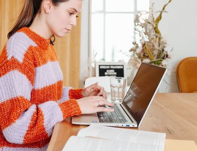 Junge Frau sitzt am Schreibtisch, vor ihr steht ein aufgeklappter Laptop, Foto: Grit Hartung