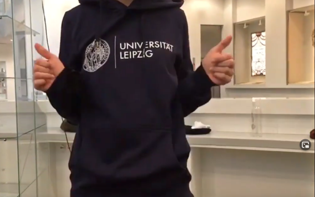 Close-up of a torso wearing a blue leipzig university hoodie and giving the thumbs up