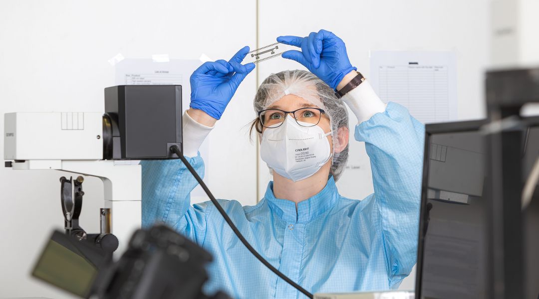 Doctoral researcher with a microfluidics chip (Photo: Swen Reichhold / Leipzig University, RTG 2721)