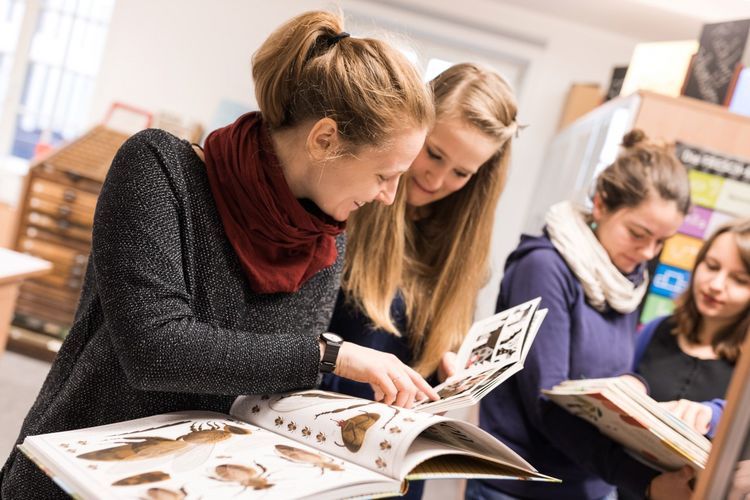 Zwei Studentinnen schauen gemeinsam in ein Kinderbuch für Insekten, Foto: Christian Hüller