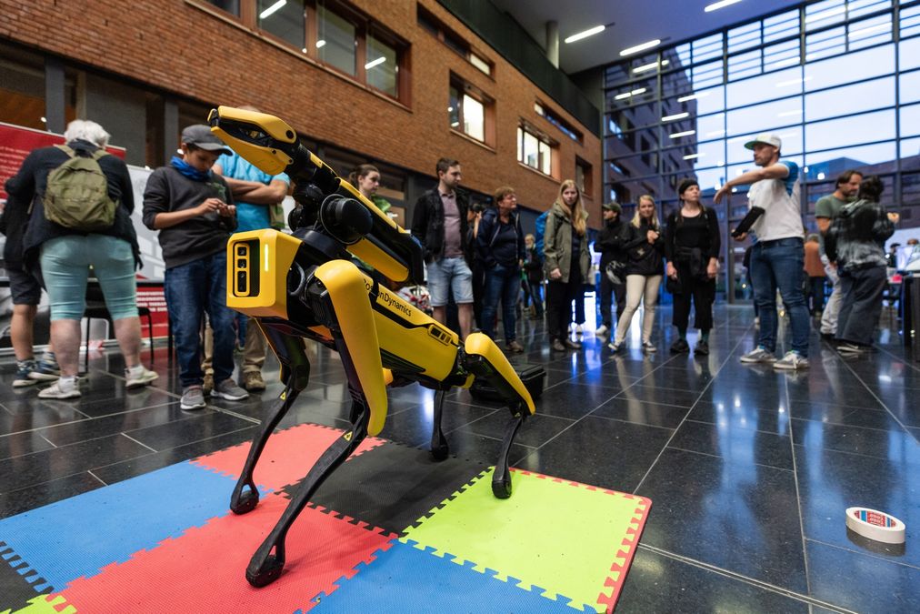 zur Vergrößerungsansicht des Bildes: Das Atrium der Biocity mit einem gelben Roboterhund um den herum mehrere Besucher stehen 