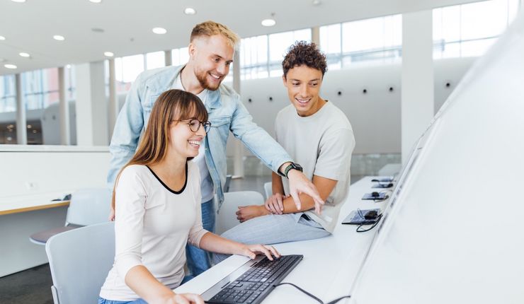 Three students in front of a PC workstation in the foyer of the New Augusteum at Leipzig University