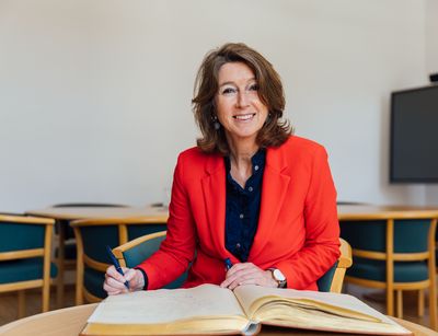 Hester Somsen, Botschafterin Seiner Majestät des Königs der Niederlande in Berlin, sitzt vor dem Goldenen Buch, einen Stift in der Hand.