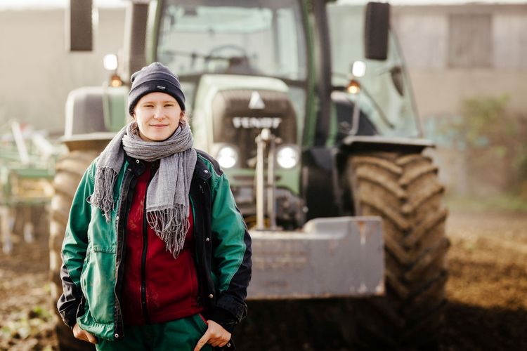 Mara vor einem Traktor auf dem Feld.