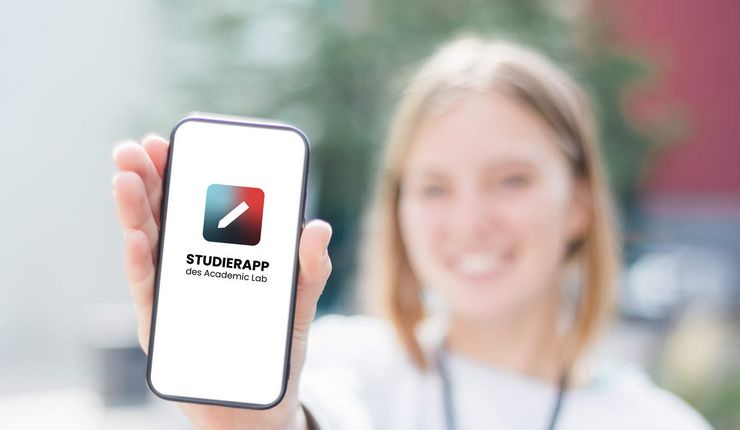 Eine Studentin hält ein Smartphone mit geöffneter Studierapp. Foto: Academic Lab