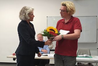 Zu sehen ist, wie Rektorin Obergfell Felix Fink als Dank eine Ukrunde und einen Blumenstrauß überreicht.