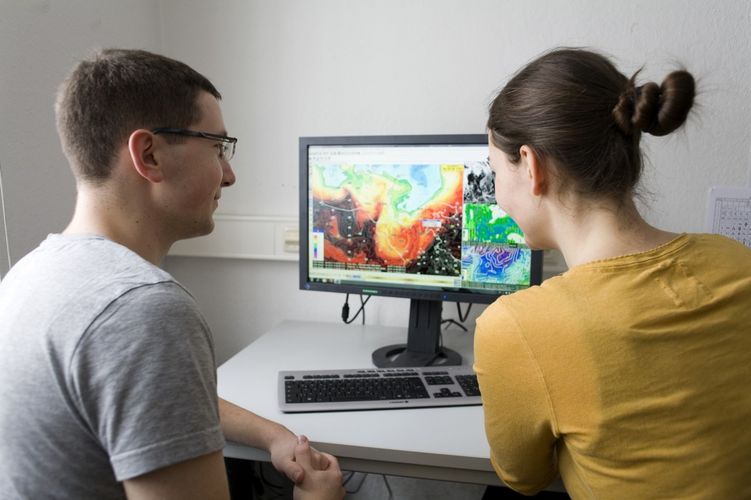 Zwei Studierende sitzen vor einem Bildschirm, auf dem unterschiedliche Wetterkarten zu sehen sind, Foto: Christian Hüller