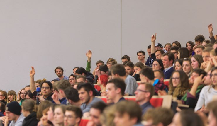 Foto: zuhörer im Hörsaal die sich zum Teil melden