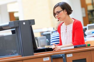Foto: Eine Junge Frau sitzt in der Universitätsbibliothek am Laptop