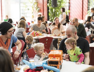 Foto: Eltern, die mit ihren Kindern beim Frühstück in der Mensa sitzen