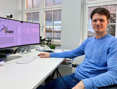  Man sitting at his desk in front of the computer, but facing the camera