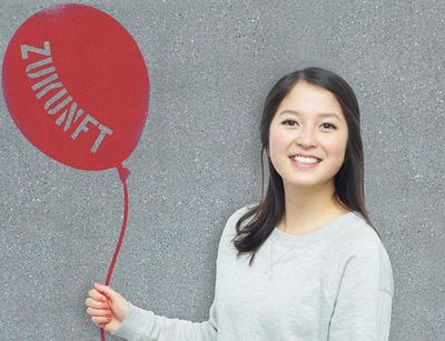 Optimistische Studentin hält Ballon mit Aufschrift "Zukunft"