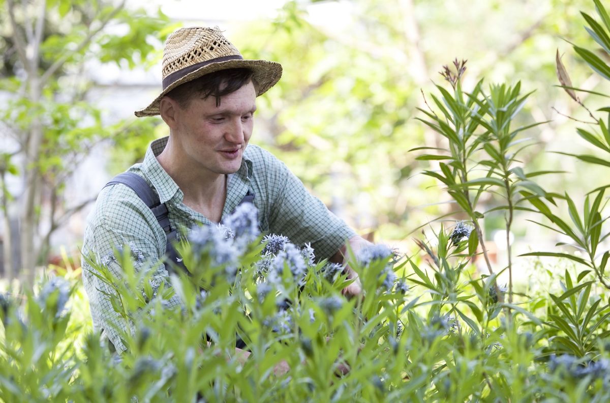 Foto: ein Gärtner mit Strohhut hockt vor einem Beet 