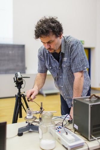 Lecturer stands bent over an experimental setup