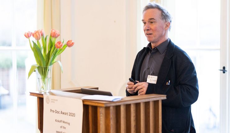 Prof. Dr. Erich Schröger steht hinter einem Rednerpult aus Holz und spricht zum Publikum.