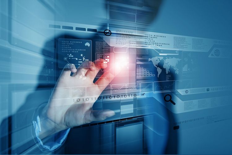 Computergrafik: Ein Mensch tippt auf ein virtuelles Display und Zahlencodes erscheinen. Im Hintergrund der Grafik steht eine Person in fotorealistischer Darstellung. Sie wendet sich Richtung Kamera und tippt mit dem rechten Zeigefinger wie auf eine Glasscheibe direkt vor ihr. Die Person ist nur zum Teil zu sehen, Kopf und Unterkörper sind angeschnitten. Die Person ist nur unscharf zu erkennen. Der Fokus des Bildes liegt auf dem Zeigefinger, der auf ein virtuelles Display tippt und damit Computerprogramme steuert und Daten abruft. An der Stelle, an der der Finger das unsichtbare Display berührt, entsteht ein heller Lichtpunkt.