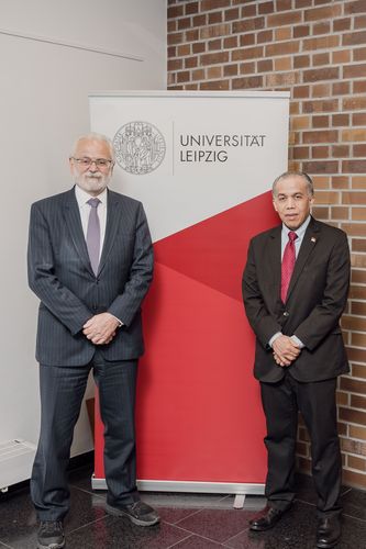 Auf dem Bild sind der Der brasilianische Botschafter in Deutschland, Roberto Jaguaribe Gomes de Mattos (links), und der stellvertretende Botschafter der Republik Indonesien in Deutschland, Yul Edison, vor einem Banner der Universität Leipzig zu sehen.