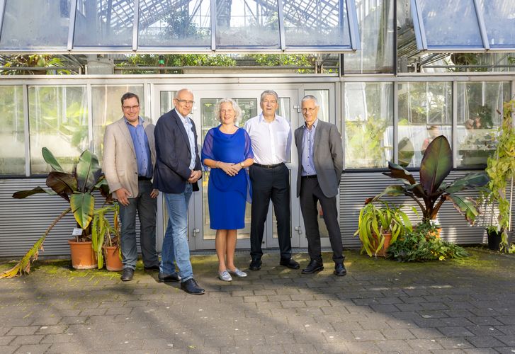 Professor:innen der Universität Leipzig stehen vor einem Gewächshaus im Botanischen Garten