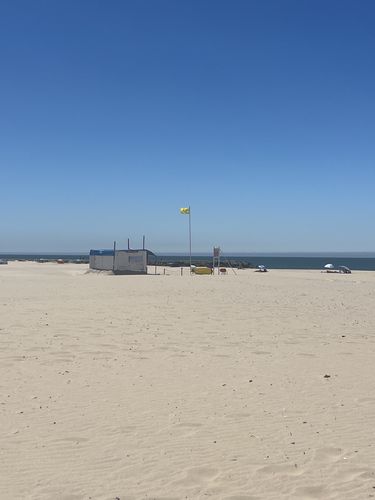 weiter Strand an der nördlichsten Spitze von Costa da Caparica mit blauem Himmel im Hintergrund