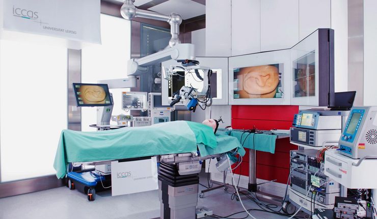 Farbfoto eines Operationssaales mit verschiedenen technischen Geräten und einem Dummy-Menschen auf einer Liege